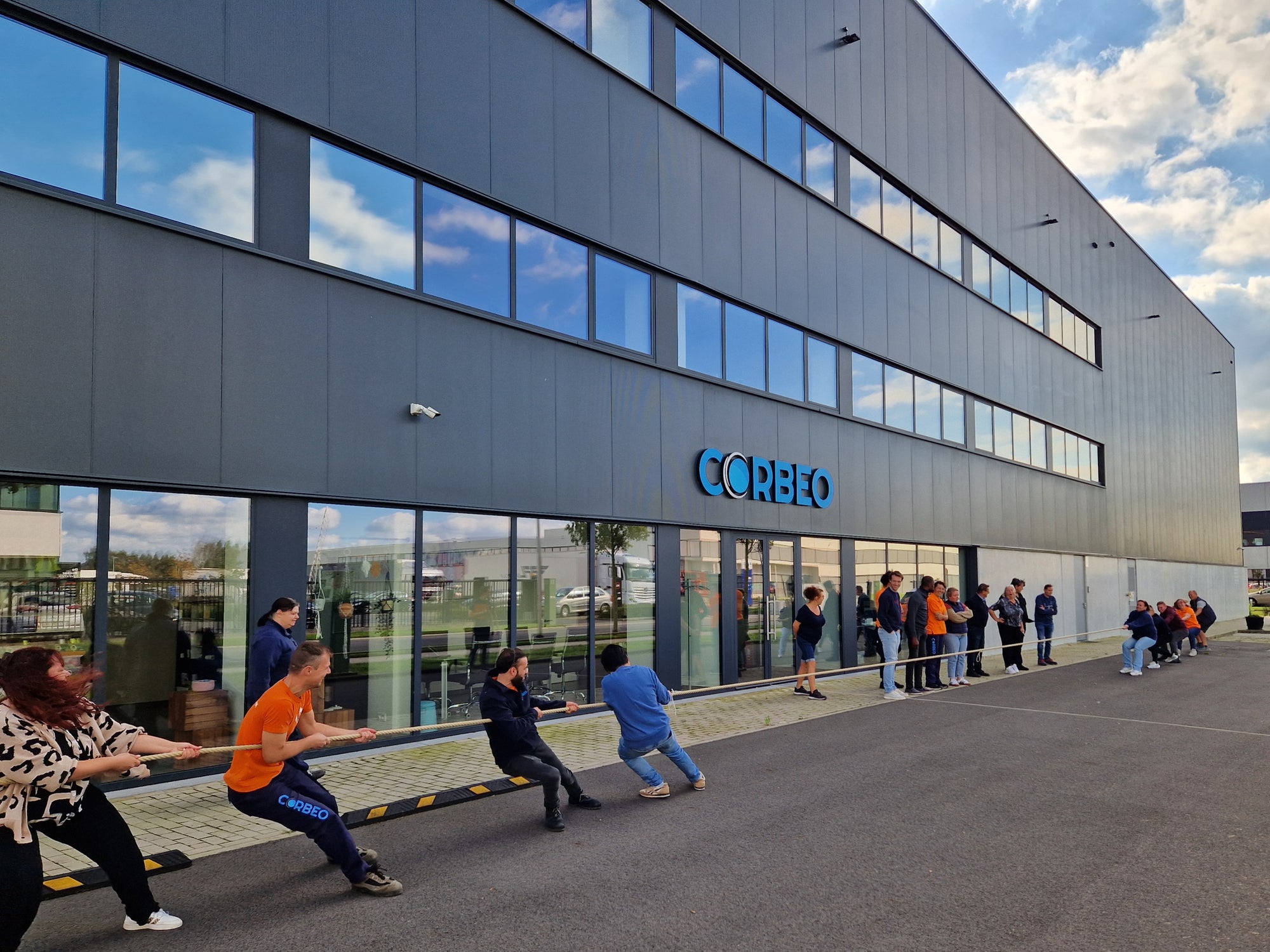 People pulling a cord beside a building.
